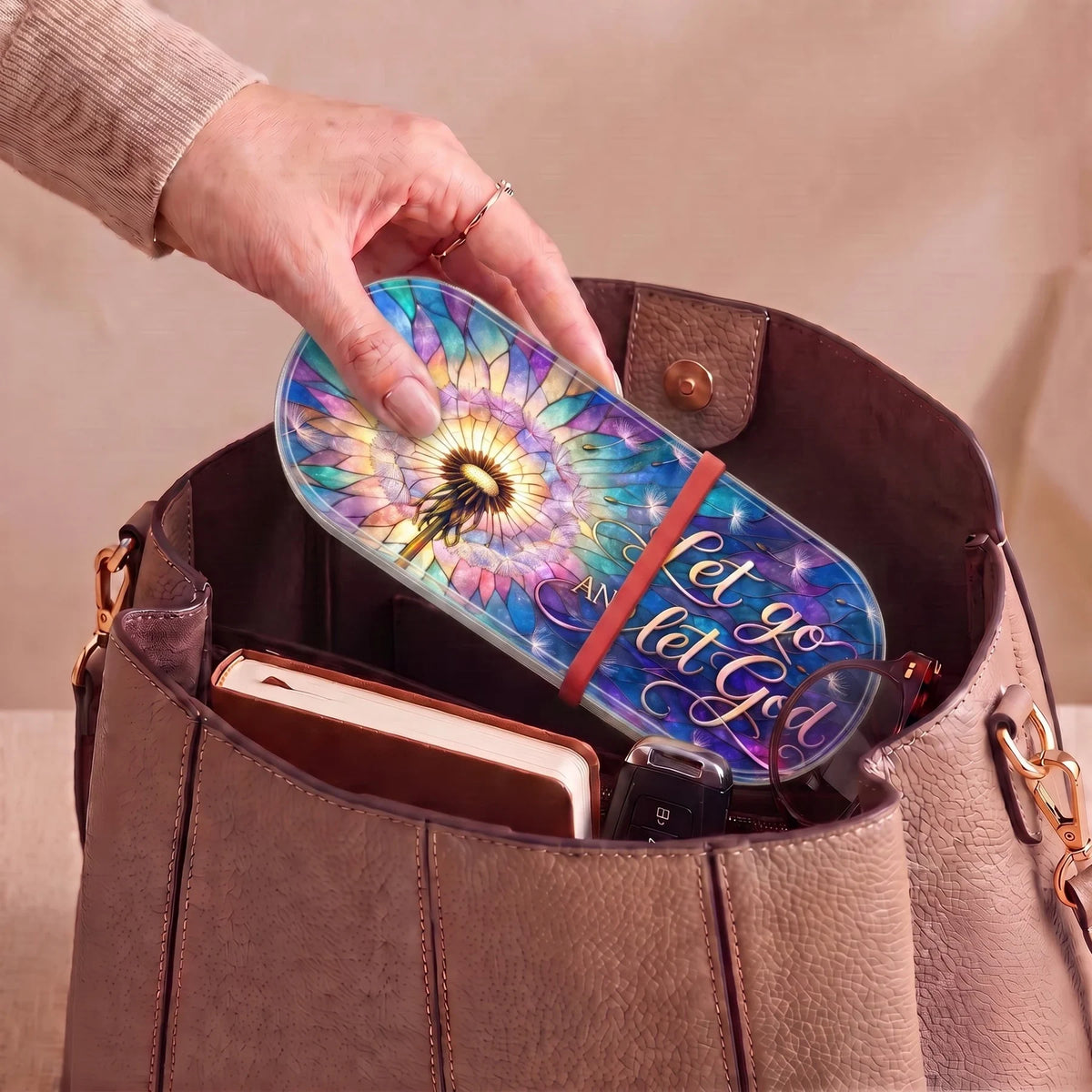 Let Go and Let God dandelion Pillcase carried inside a handbag with everyday essentials