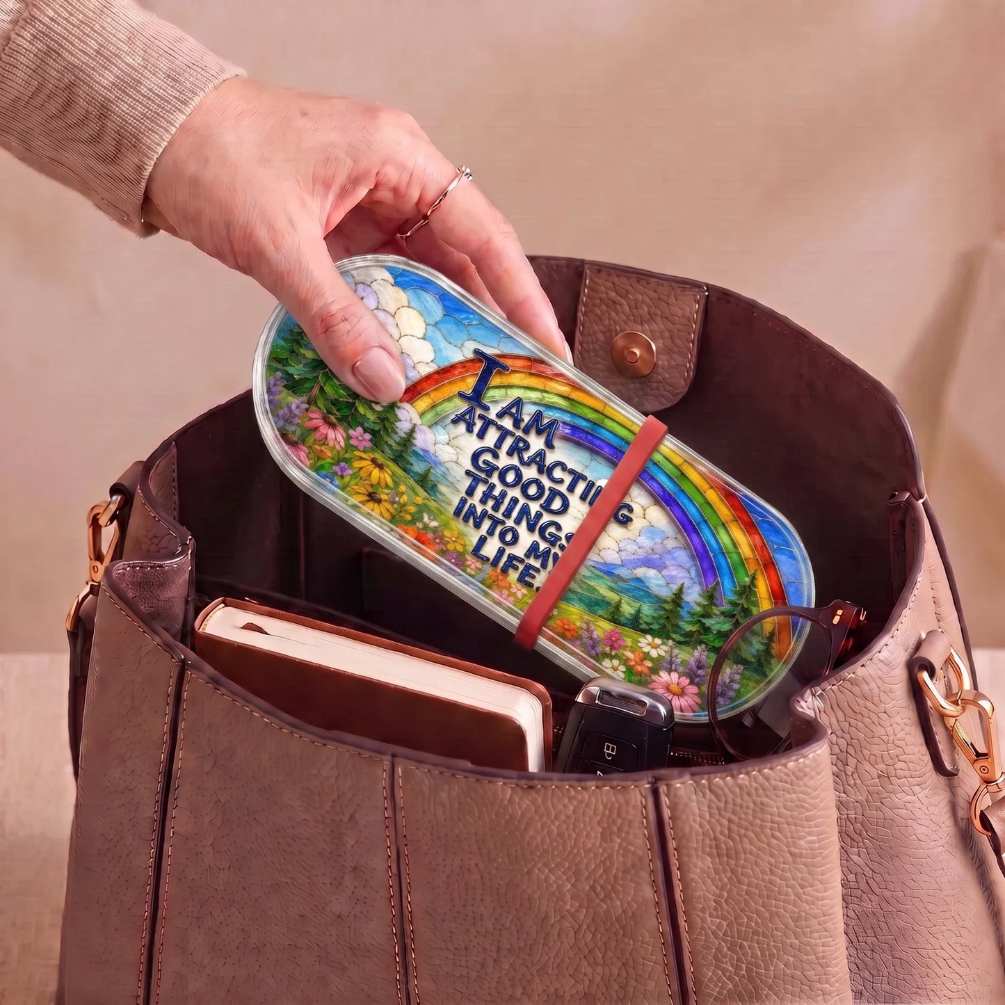 I Am Attracting Good Things rainbow Pillcase carried inside a handbag with everyday essentials