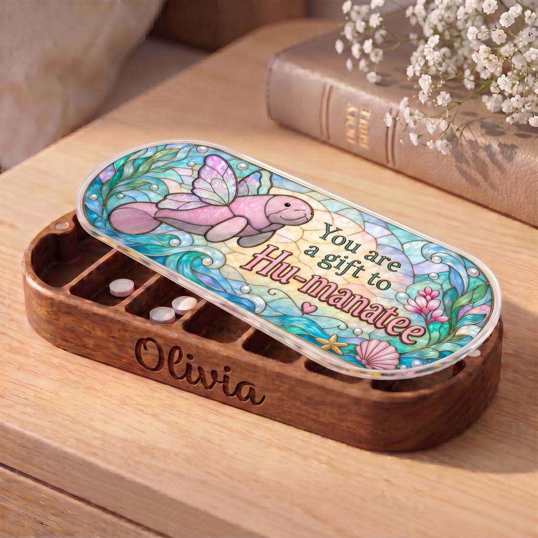 "You Are a Gift to Hu-manatee — Winged Manatee Stained Glass" Pill Case — personalized open Hu-manatee Pill Case on a wooden table