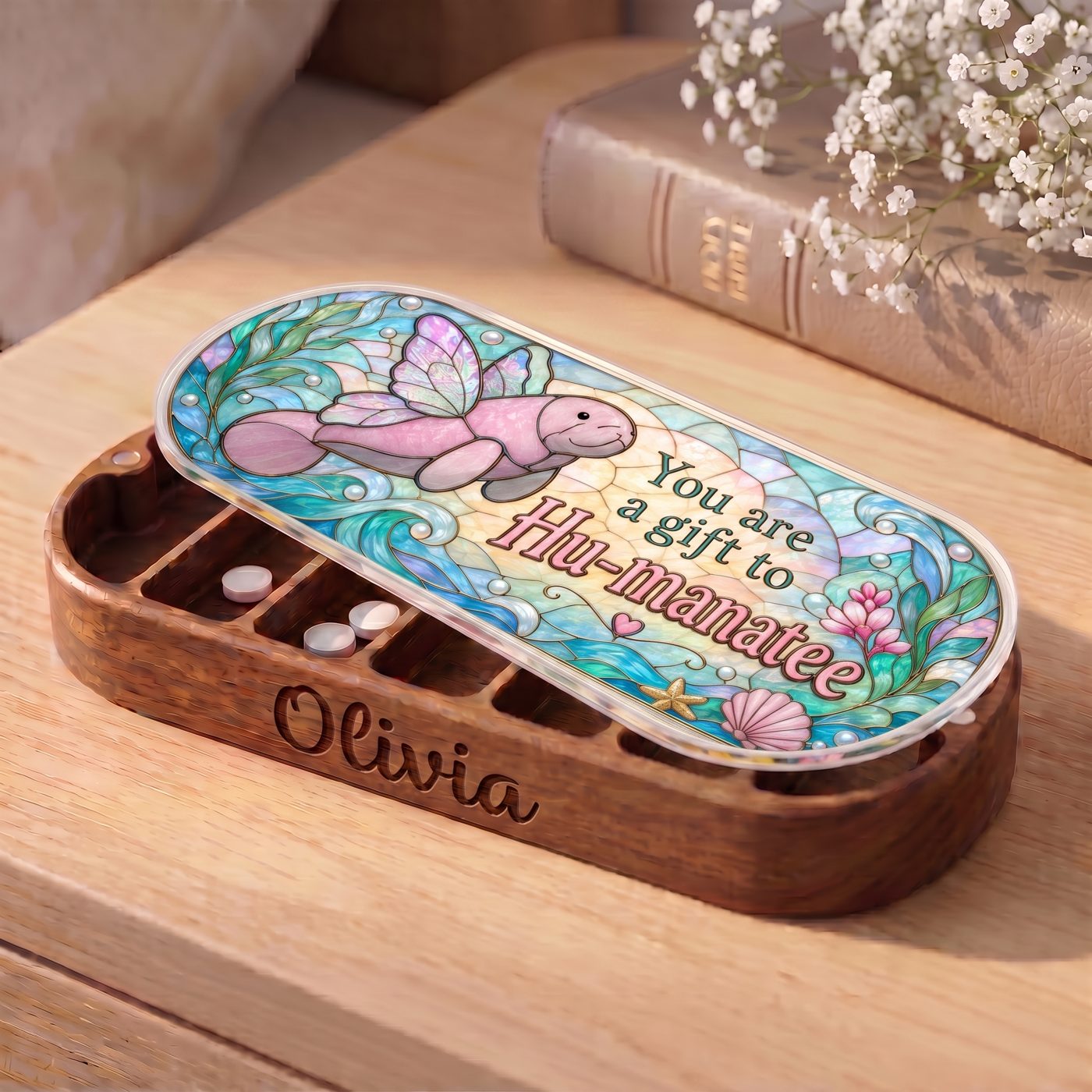 "You Are a Gift to Hu-manatee — Winged Manatee Stained Glass" Pill Case — personalized open Hu-manatee Pill Case on a wooden table