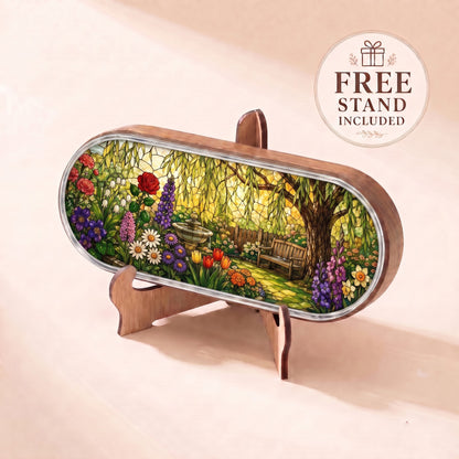 Peaceful Garden Retreat Pillcase with willow tree, wooden bench and colorful flowers displayed on included stand