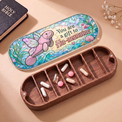 "You Are a Gift to Hu-manatee — Winged Manatee Stained Glass" Pill Case — open Hu-manatee Pill Case with Holy Bible, white flowers, and assorted pills