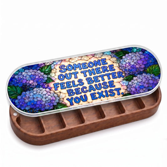 Open wooden Someone Out There Feels Better Because You Exist Pillcase with blue hydrangeas on a stained-glass-style lid on white